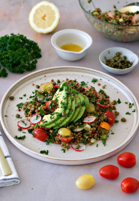 Insalatona di lenticchie con fette di avocado, ravanelli, pomodorini, capperi ed erbe