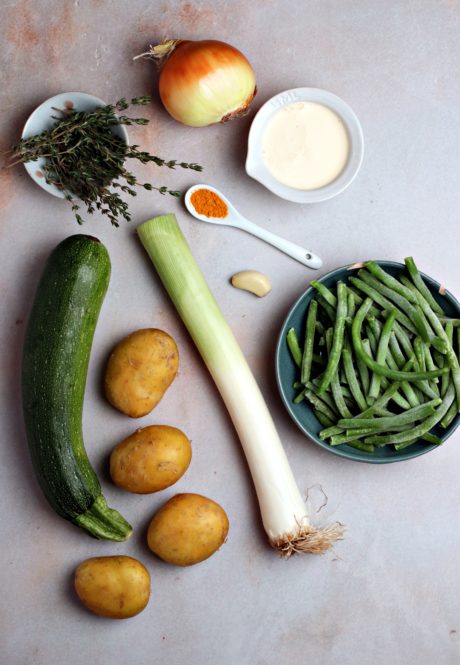 Ingredienti per il minestrone di zucchine: cipolla, patate, aglio, zucchina, curcuma, panna, timo fresco